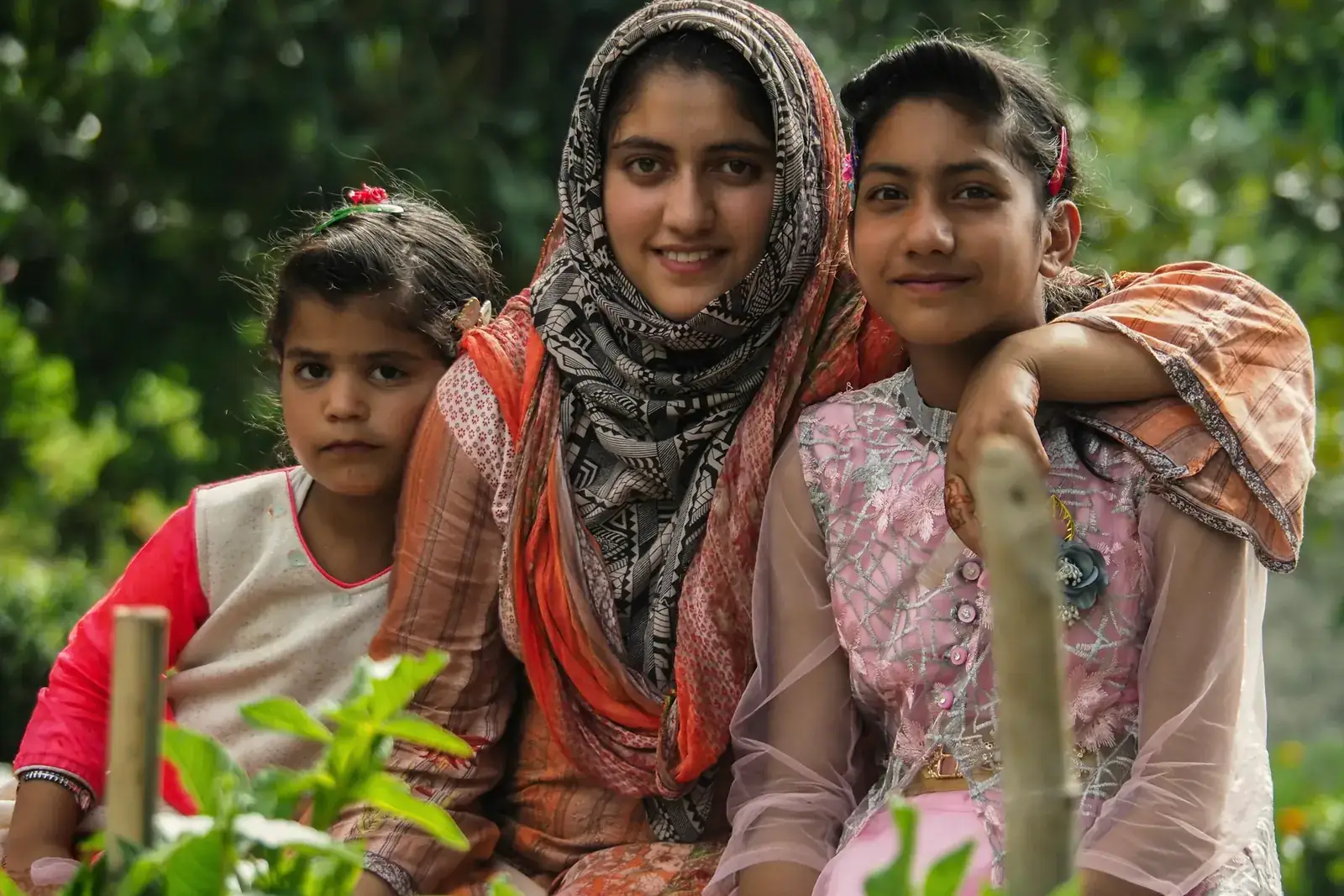 A mother and two girls smiling together outside their home