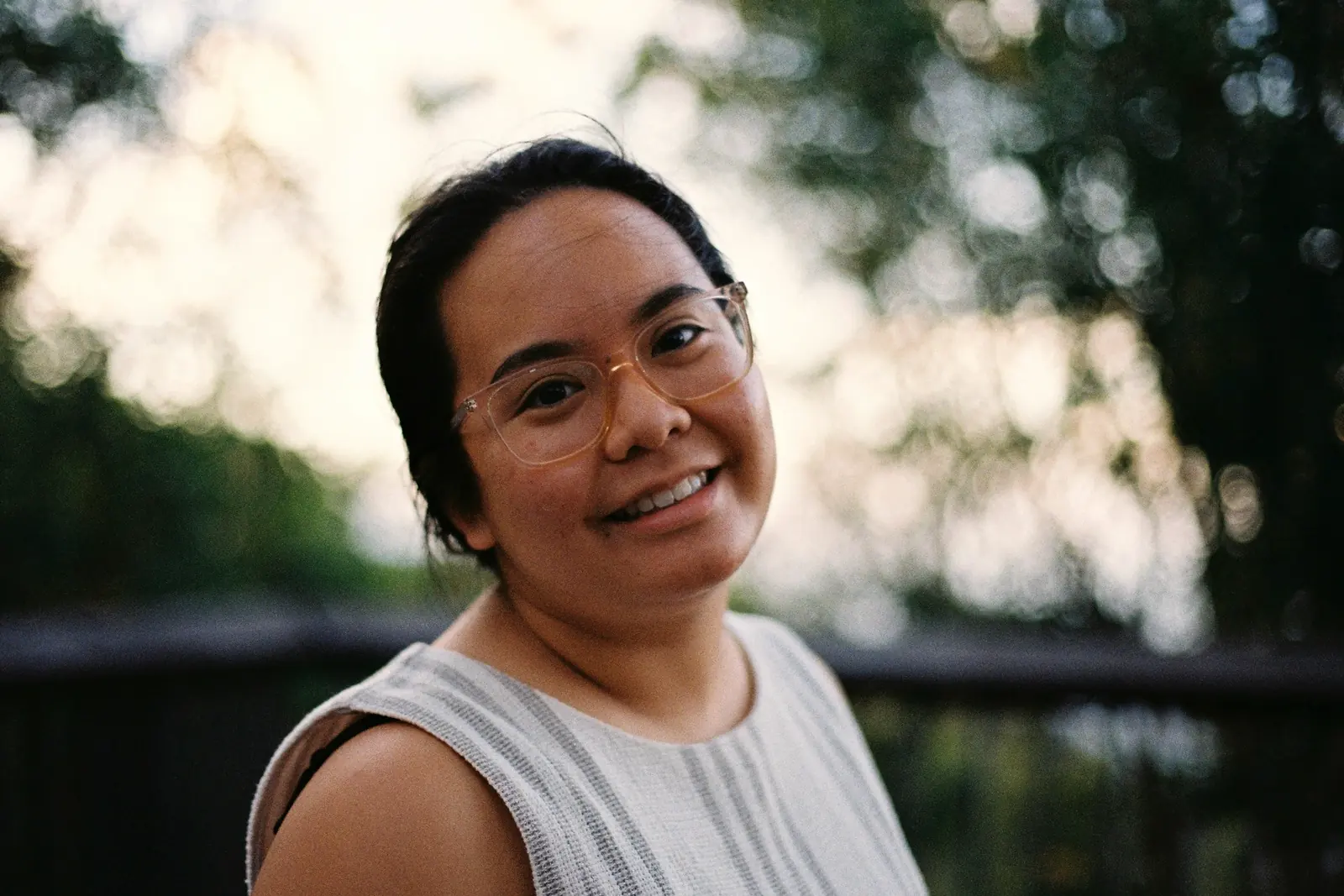 A woman smiling outdoors in soft morning light