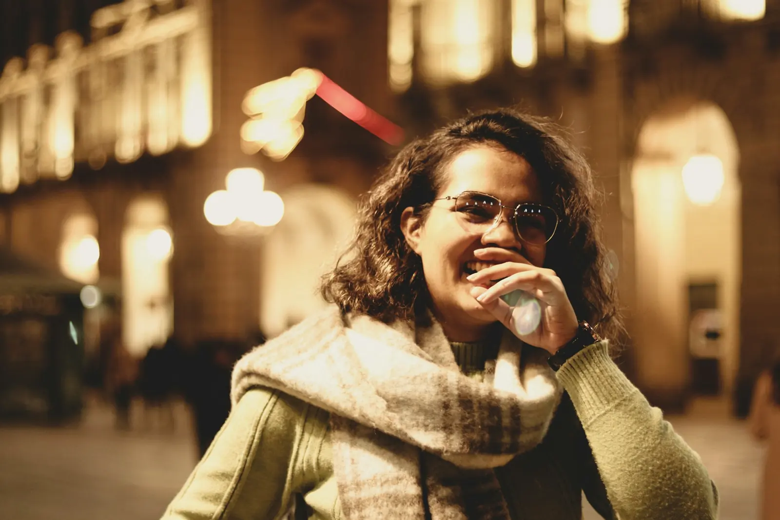 A young woman smiling on a city street at night